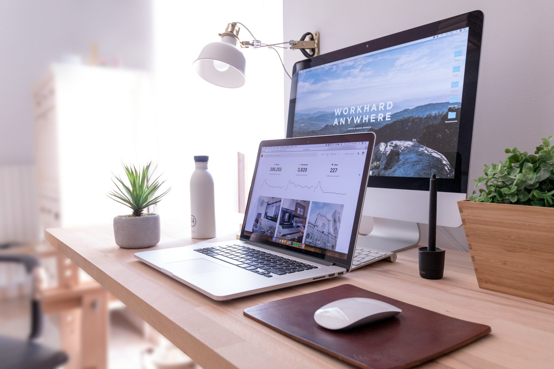MacBook Pro sobre una mesa junto a un iMac blanco y un Magic Mouse